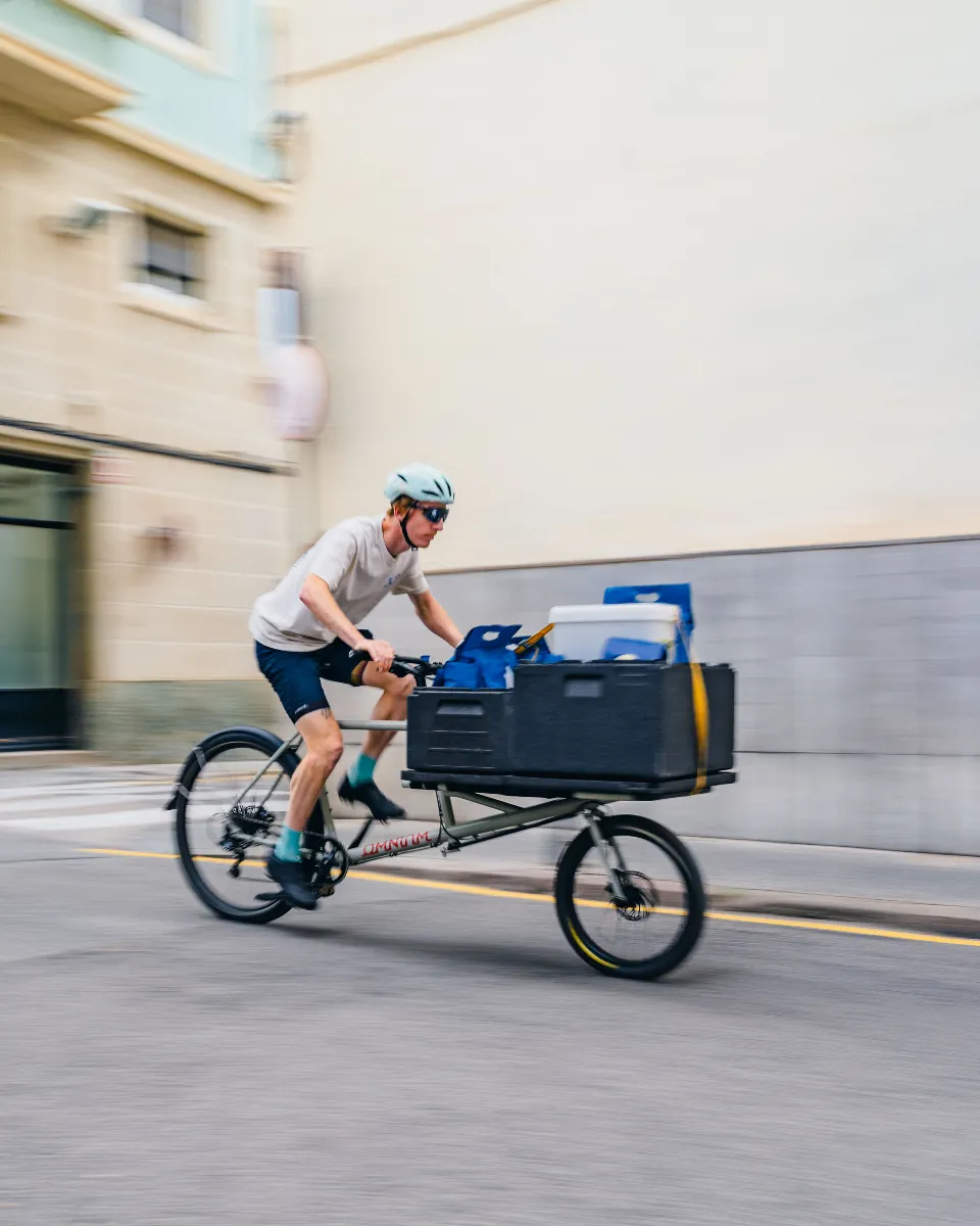 Earlybird rider speeding down a Barcelona street on a cargo bike with a full crate
