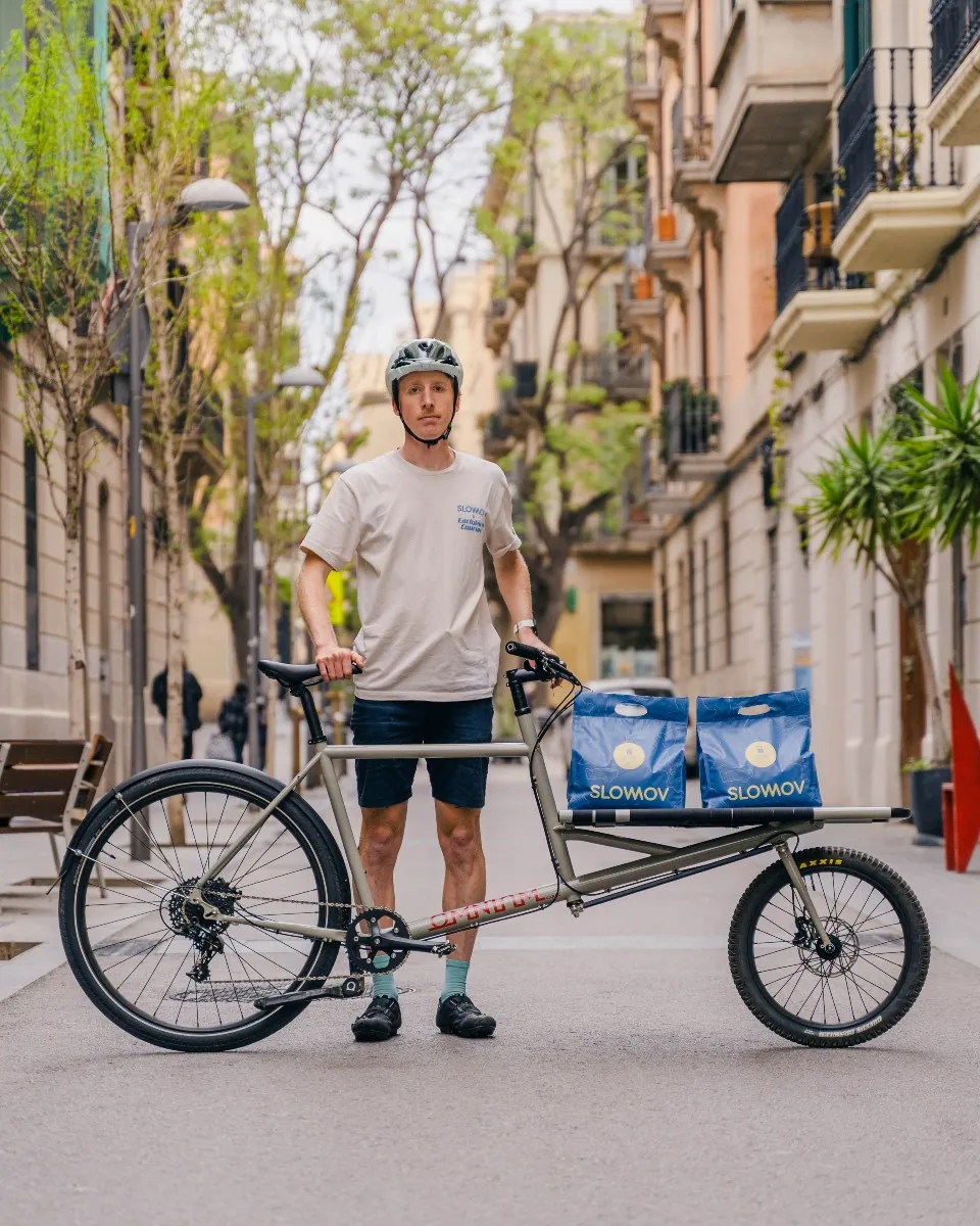 Earlybird rider in an Earlybird Courier t-shirt with two Slowmov coffee bags on his cargo bike